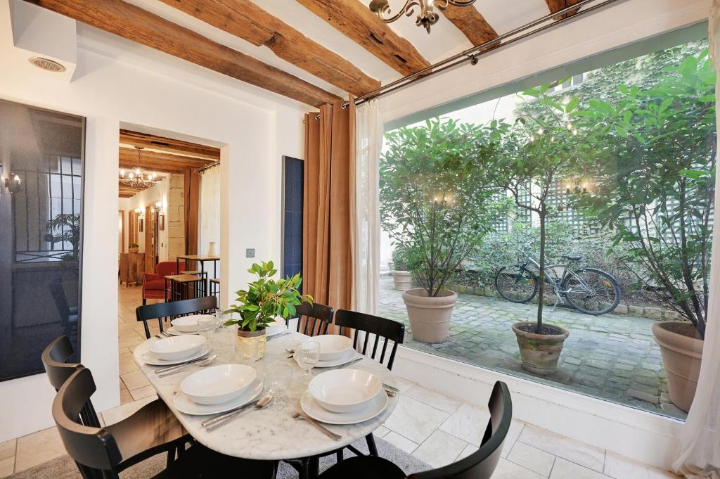une salle à manger avec une table et des chaises et une grande fenêtre dans l'établissement Elegant apartment - 2BR-7P - Quartier latin, à Paris