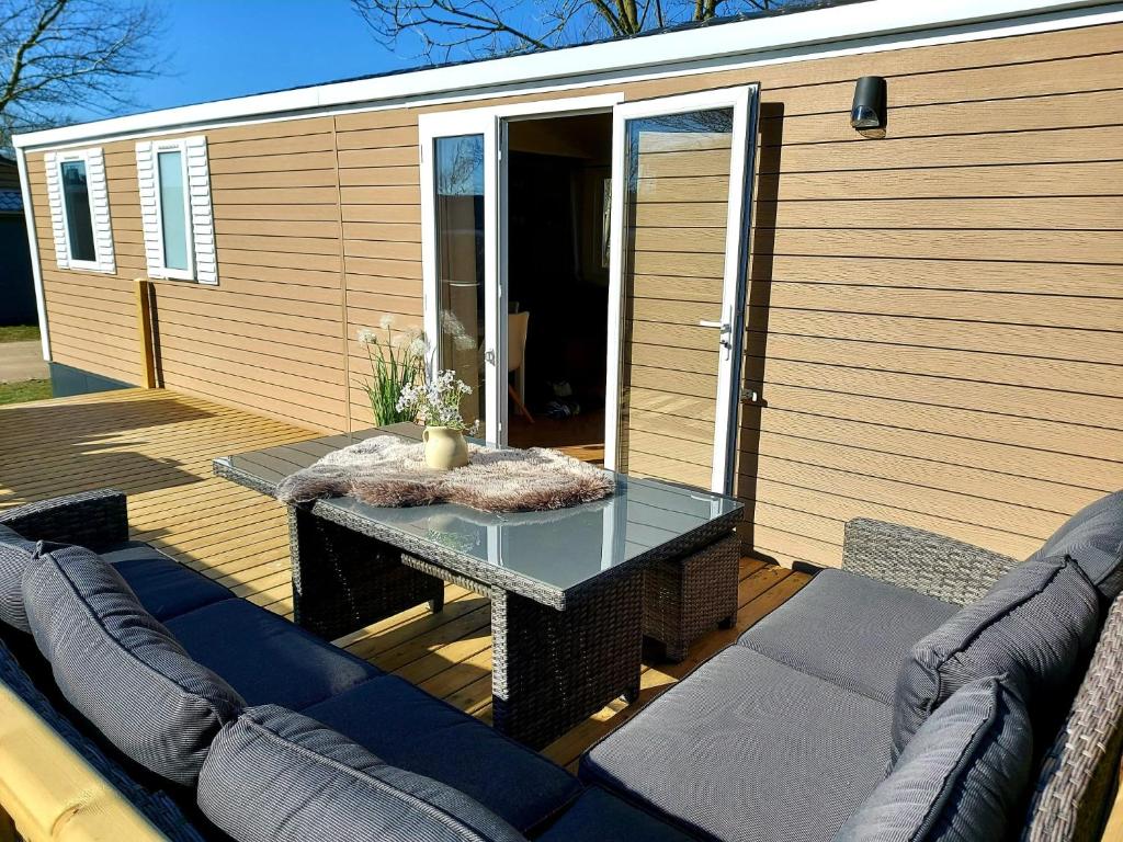 a patio with a table and a couch on a deck at Luxe Chalet Lauwersoog in Lauwersoog