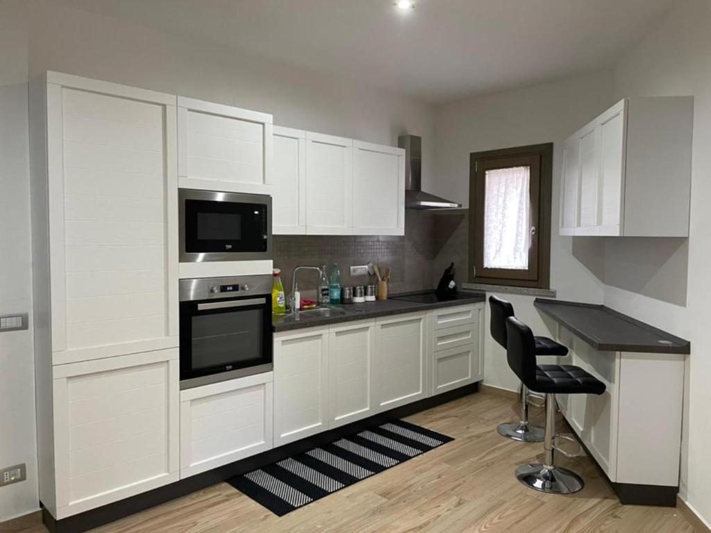 a kitchen with white cabinets and a stove top oven at Casa Manzoni in La Maddalena