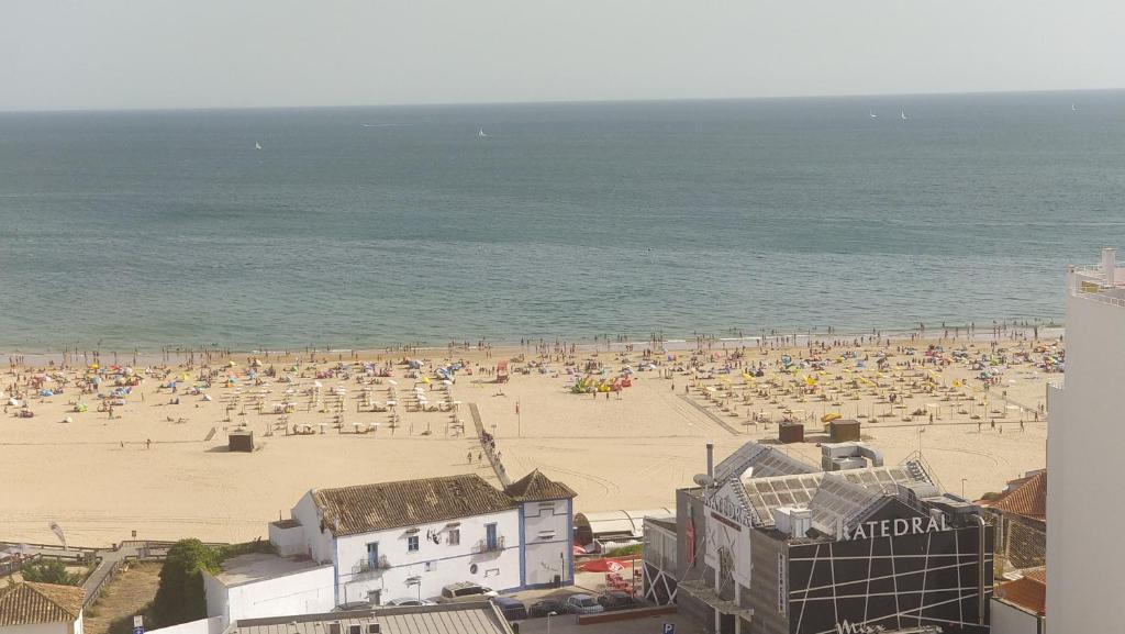 una spiaggia con molti ombrelloni e l'oceano di Apartamento com grandes terraços em frente a Praia a Portimão