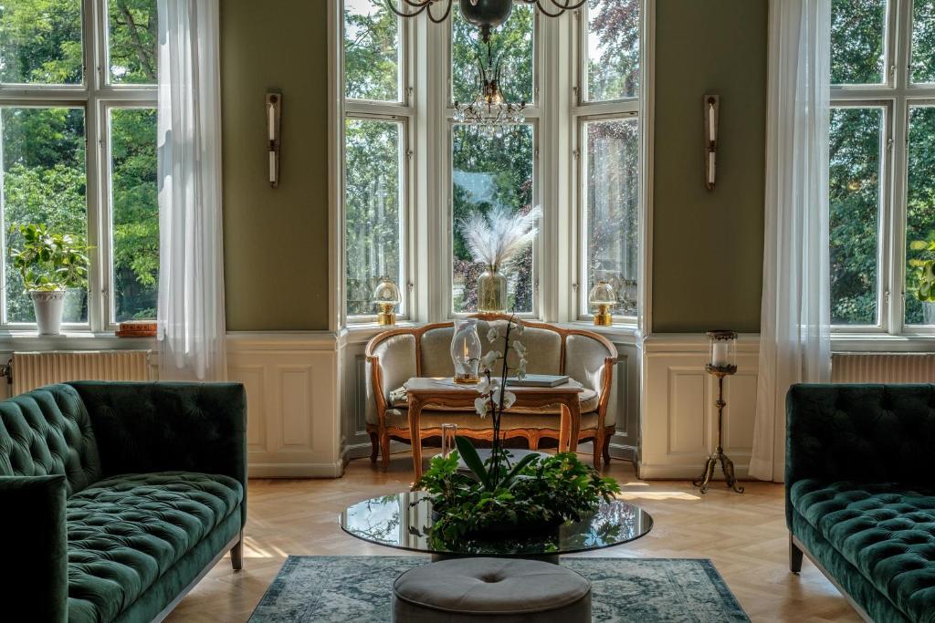 a living room with chairs and a table and windows at Fredensborgs Herrgård in Vimmerby