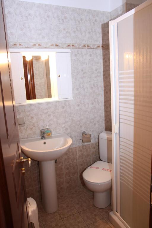 a bathroom with a sink and a toilet and a mirror at Artemis Traditional Hotel in Myrina
