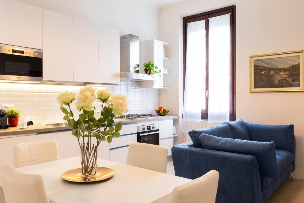 a kitchen and living room with a table and a blue couch at BICOCCA HOME - 2 Bedrooms in Milan