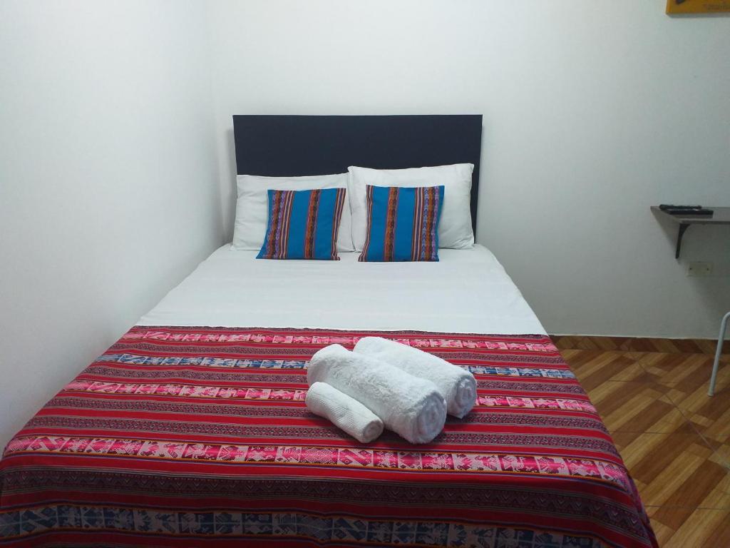 a bedroom with a bed with two towels on it at Chakana Family Home 2 Lima Airport in Lima