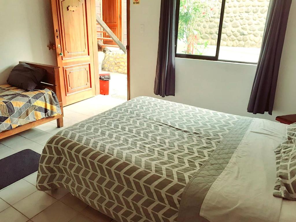 1 dormitorio con 1 cama en una habitación con ventana en HOSTAL EL COLIBRI, en Puyo