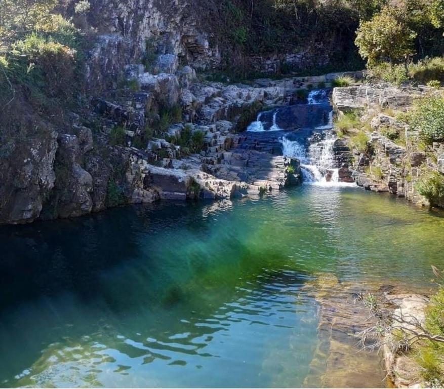 a body of water with a waterfall in the background at Pousada e Restaurante Boia Cross in Vargem Bonita