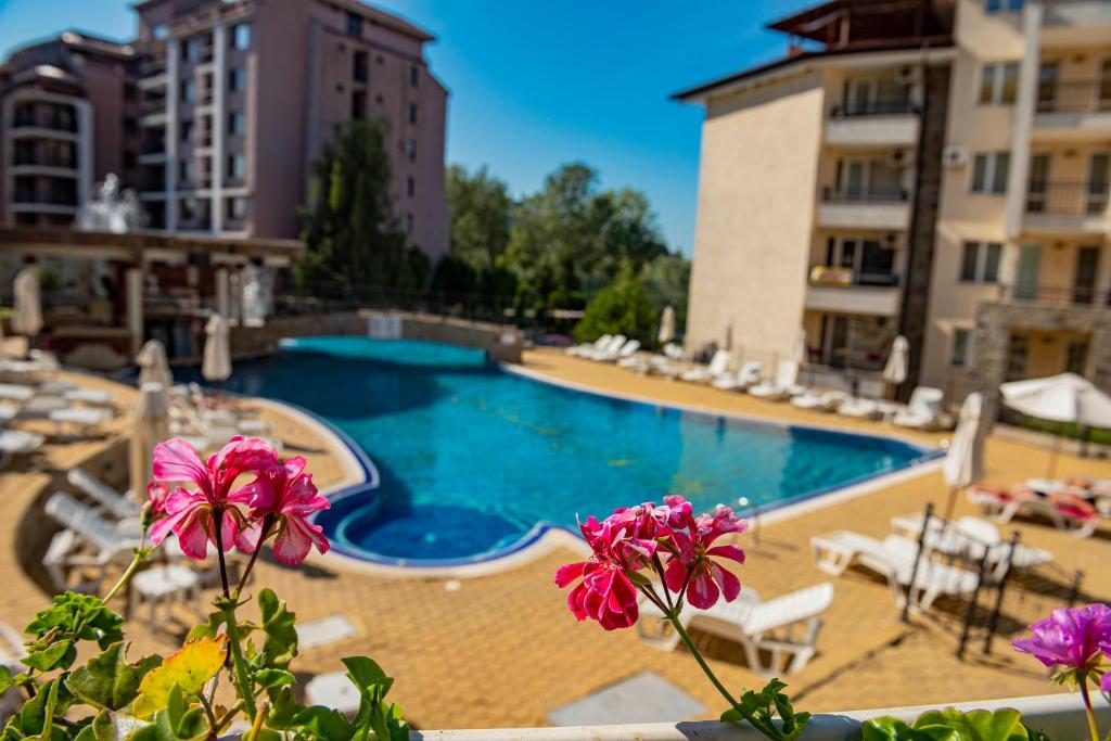 a swimming pool in front of a building with pink flowers at Sunny Beach Hills - Menada Apartments in Sunny Beach