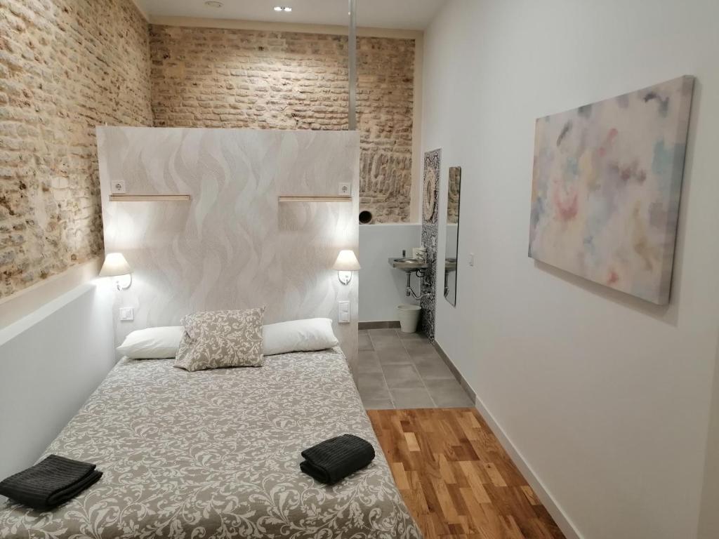 um quarto com uma cama num quarto com paredes de tijolos em SALOTUR Sierpes em Sevilha