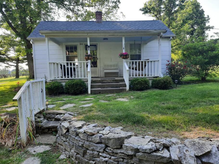 ein kleines weißes Haus mit einer Veranda und einer Steinmauer in der Unterkunft Charming Cottage on a City Farm! in Lexington