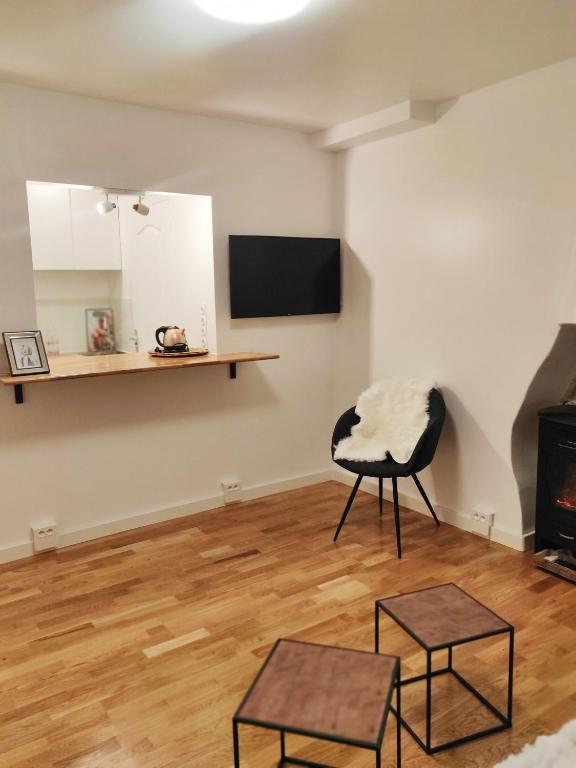 Elle comprend un salon avec une chaise et une télévision murale. dans l'établissement Chez Fanny. - studio Cosy Paris 21m2 Porte de Pantin. 2-3 pers, à Le Pré-Saint-Gervais