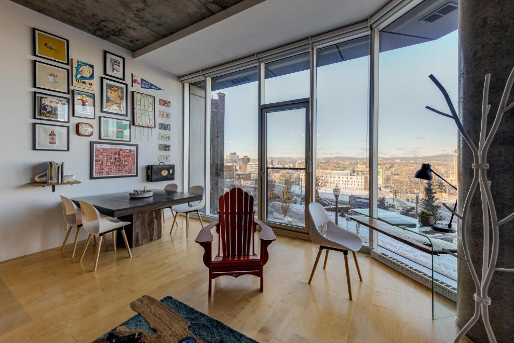 a living room with a table and chairs and a large window at Les Immeubles Charlevoix - Le 760108 in Quebec City