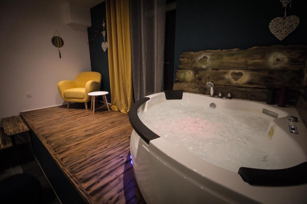 a bath tub in a room with a yellow chair at ** Au Canal du Midi - JACCUZZI & luxueux appartements ** in Carcassonne