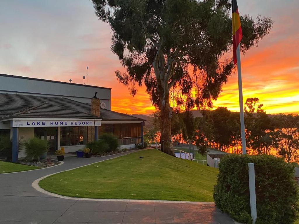 un edificio con una bandera frente a una puesta de sol en Lake Hume Resort, en Lake Hume