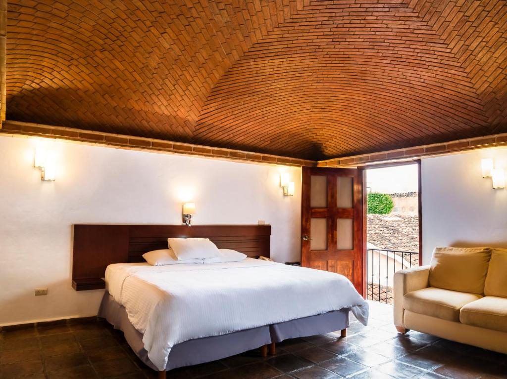 a bedroom with a large bed and a chair at Hotel Casa Real Del Café in Coatepec