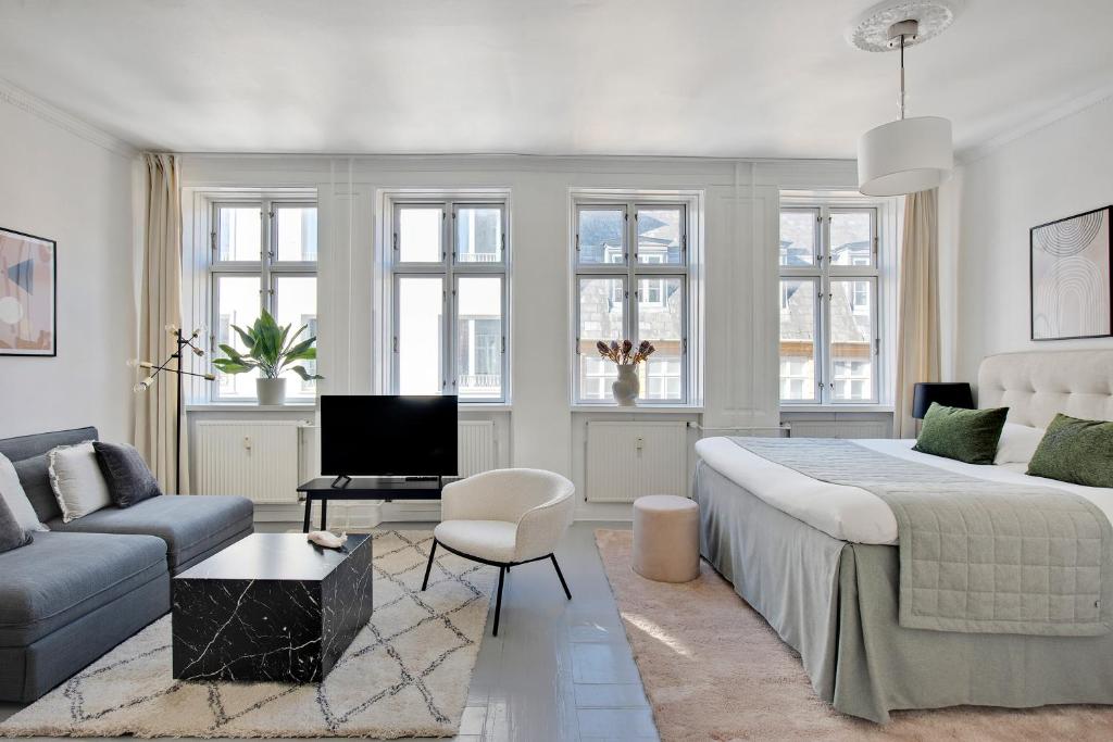 - une chambre blanche avec un grand lit et un canapé dans l'établissement Sanders City - Nimble One-Bedroom Apartment In the Lovely Capital, à Copenhague