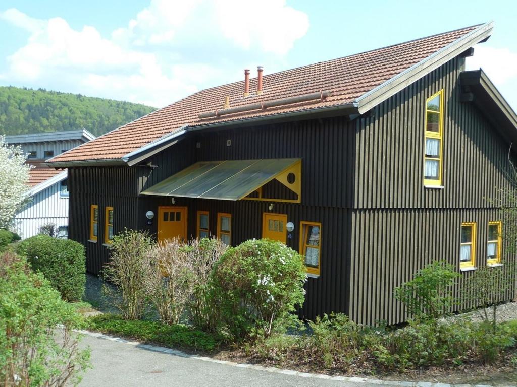 una casa negra con techo marrón en Ferienhaus Nr 6D, Feriendorf Hagbügerl, Bayr Wald, en Waldmünchen