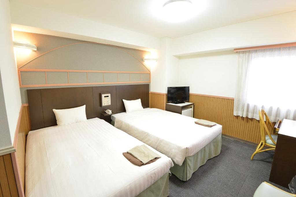 a hotel room with two beds and a television at Hotel Marutani in Tokyo