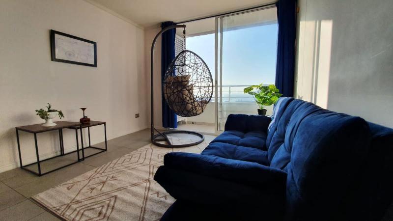a living room with a blue couch and a large window at Antofagasta Sunset - Amplio Departamento con Home Office y Vista Mar in Antofagasta