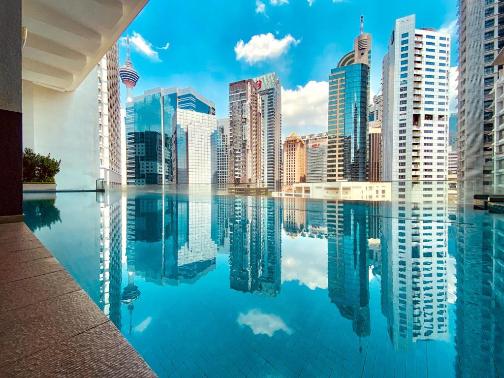 un perfil urbano reflejado en una piscina de agua en Ramada Suites by Wyndham Kuala Lumpur City Centre, en Kuala Lumpur