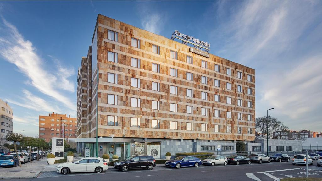 un edificio alto con coches estacionados en un estacionamiento en Sercotel Valladolid, en Valladolid