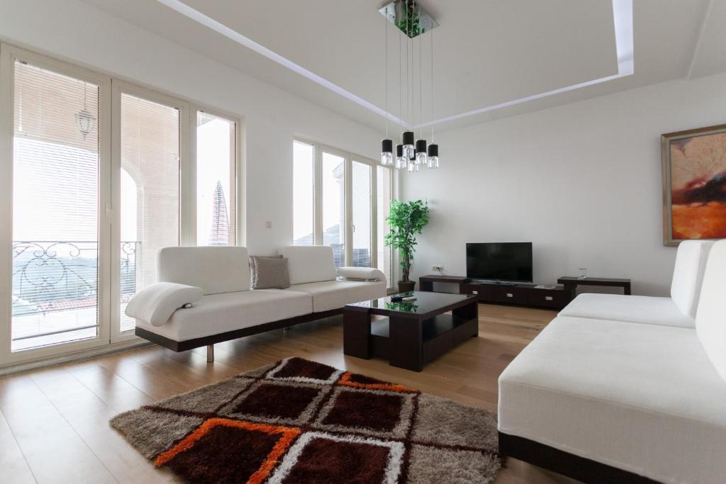 a white living room with a couch and a tv at Spa Resort Luxury Apartments in Budva