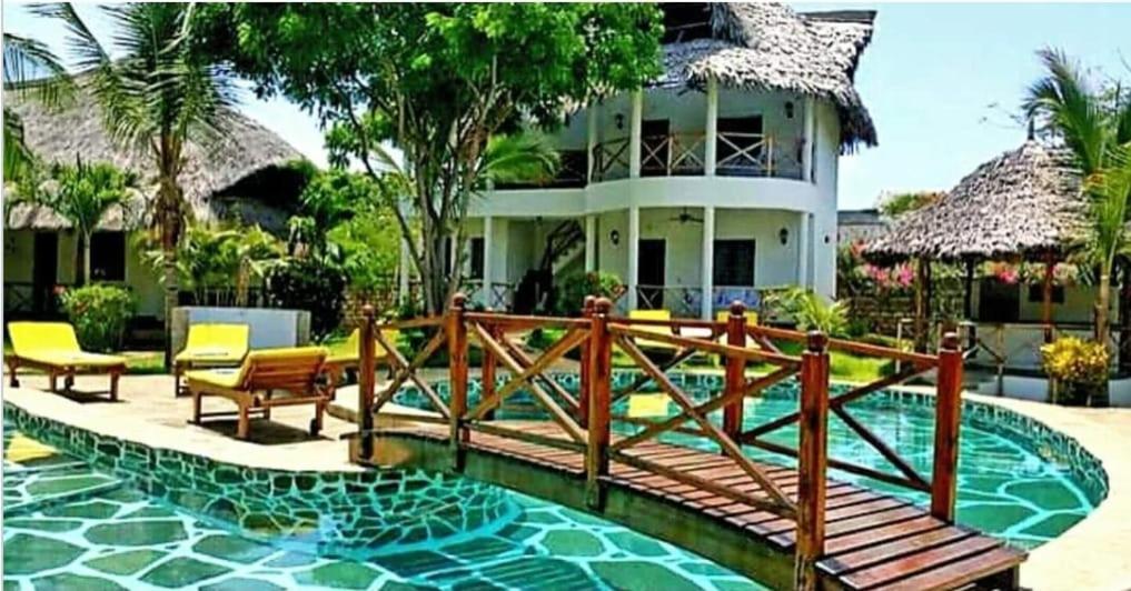 a house with a wooden bridge in front of a pool at Marine Holiday House in Malindi