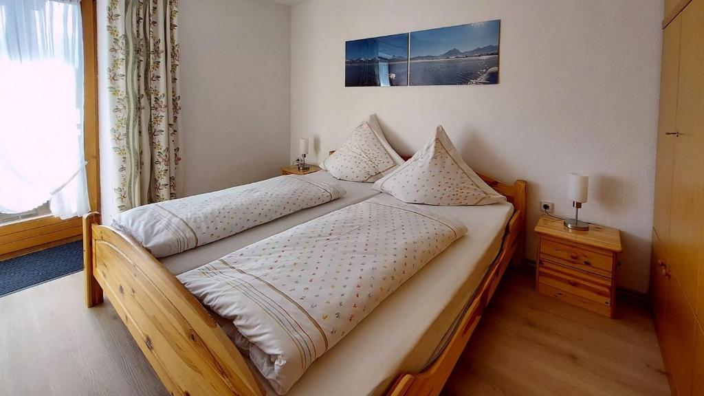una camera con letto in legno e lenzuola bianche di Ferienwohnung Nr 2, Lechbruck-Gründl, Allgäu a Prem