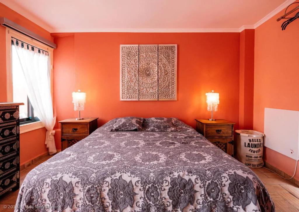 Un dormitorio con paredes naranjas y una cama con dos lámparas. en Casinha Canal - Beautifully restored Moroccan inspired townhouse in Lagos historic centre, en Lagos
