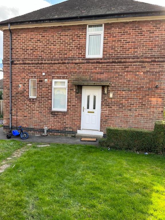 a brick house with a white door and a bike in the yard at Milnrow Road - Spacious 3 bed house 