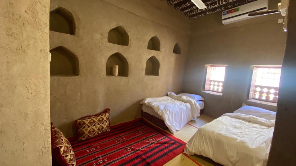 a room with two beds and a red rug at Alqalah Inn in Al Ḩamrāʼ