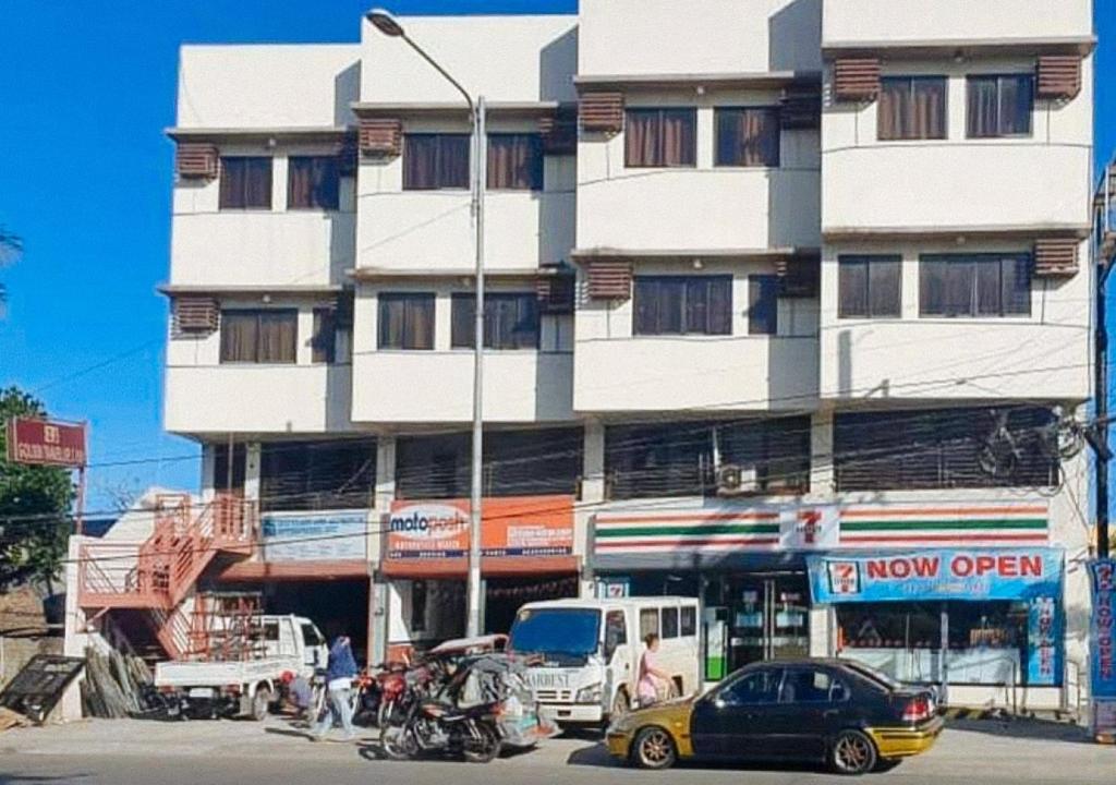 um edifício alto e branco com carros estacionados em frente em RedDoorz @ H.F. Golden Travellers Inn em Iloilo City