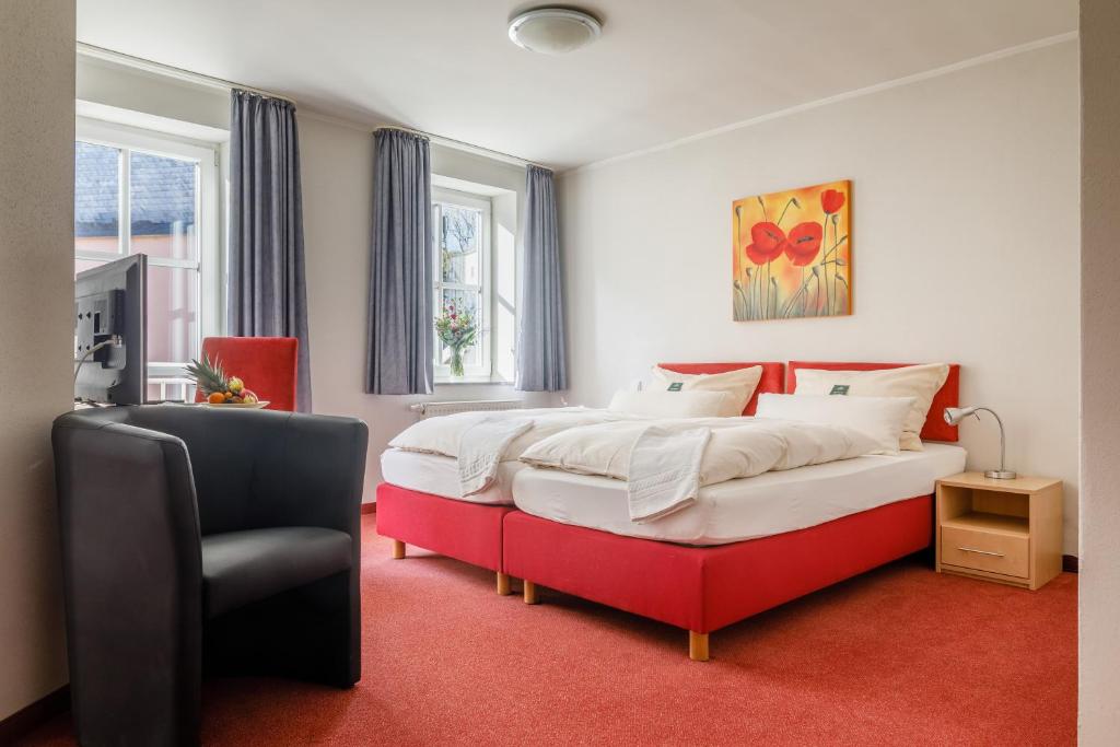 a bedroom with a large bed and a chair at Apartmenthotel Weilburg in Weilburg