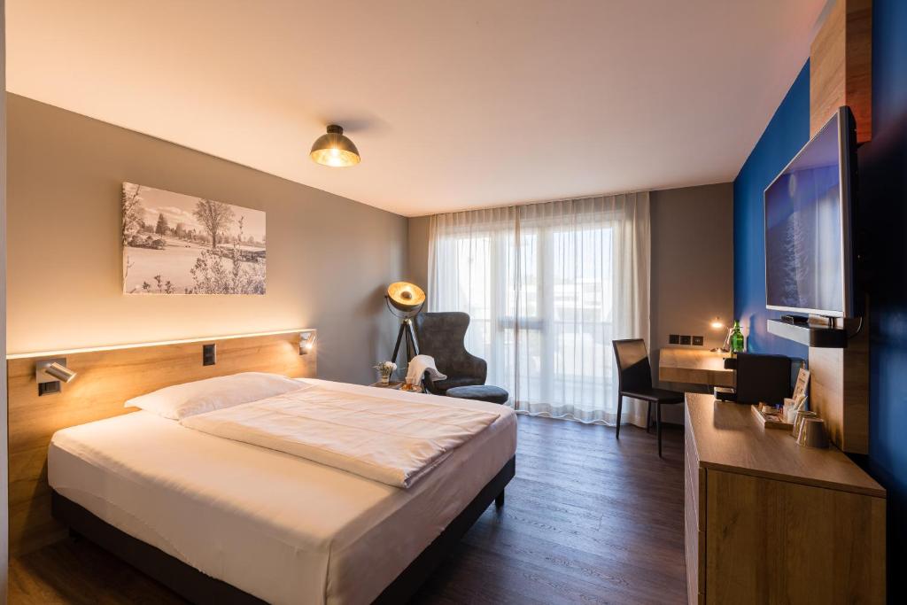 um quarto com uma cama, uma secretária e uma televisão em Aarau West Swiss Quality Hotel em Oberentfelden