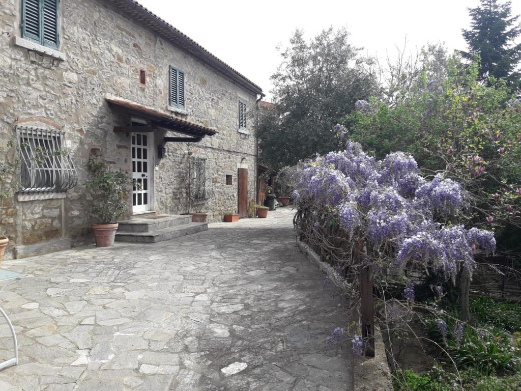 a stone building with purple flowers in front of it at Il Fico di Cortona in Cortona