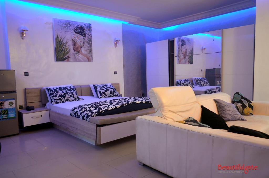 Habitación con 2 camas y sofá. en Beautifulgate Hotel, en Cotonou