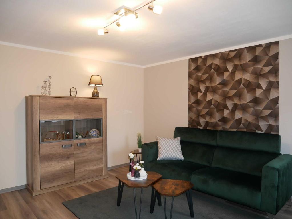 ein Wohnzimmer mit einem grünen Sofa und einem Tisch in der Unterkunft Ferienwohnung Mecklenburgische Seenplatte in Schwichtenberg