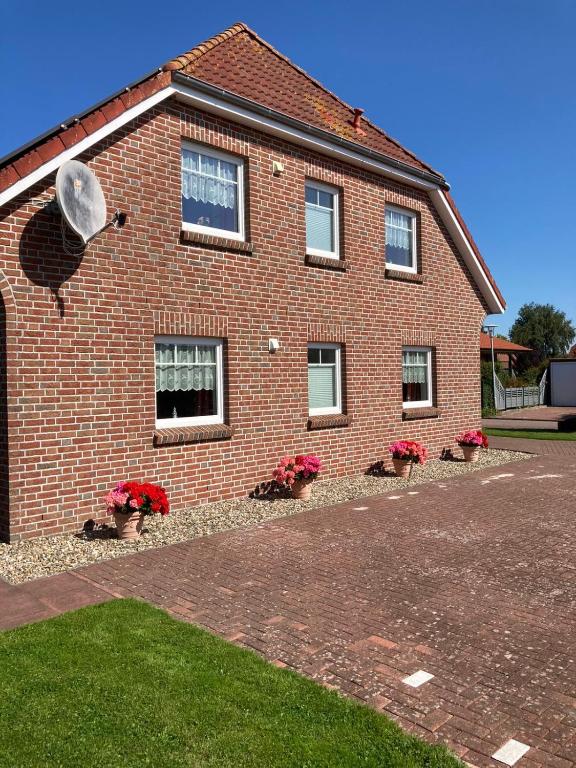 a brick house with potted plants in front of it at Ferienwohnungen Koch OG adult only in Wangerland