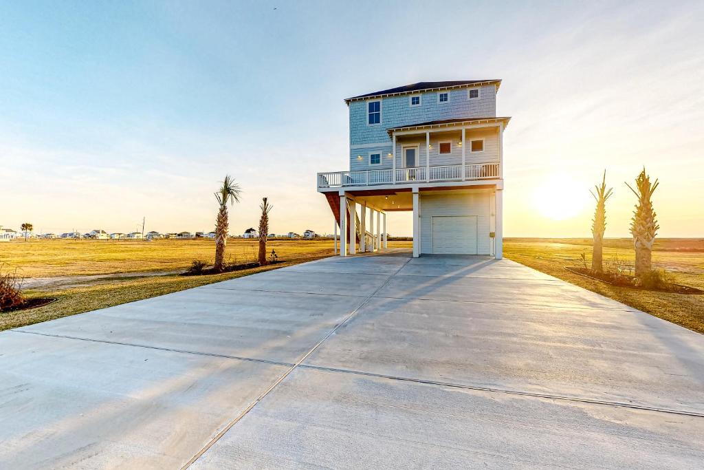 a house on a concrete road with palm trees at Sunset Bay in Galveston