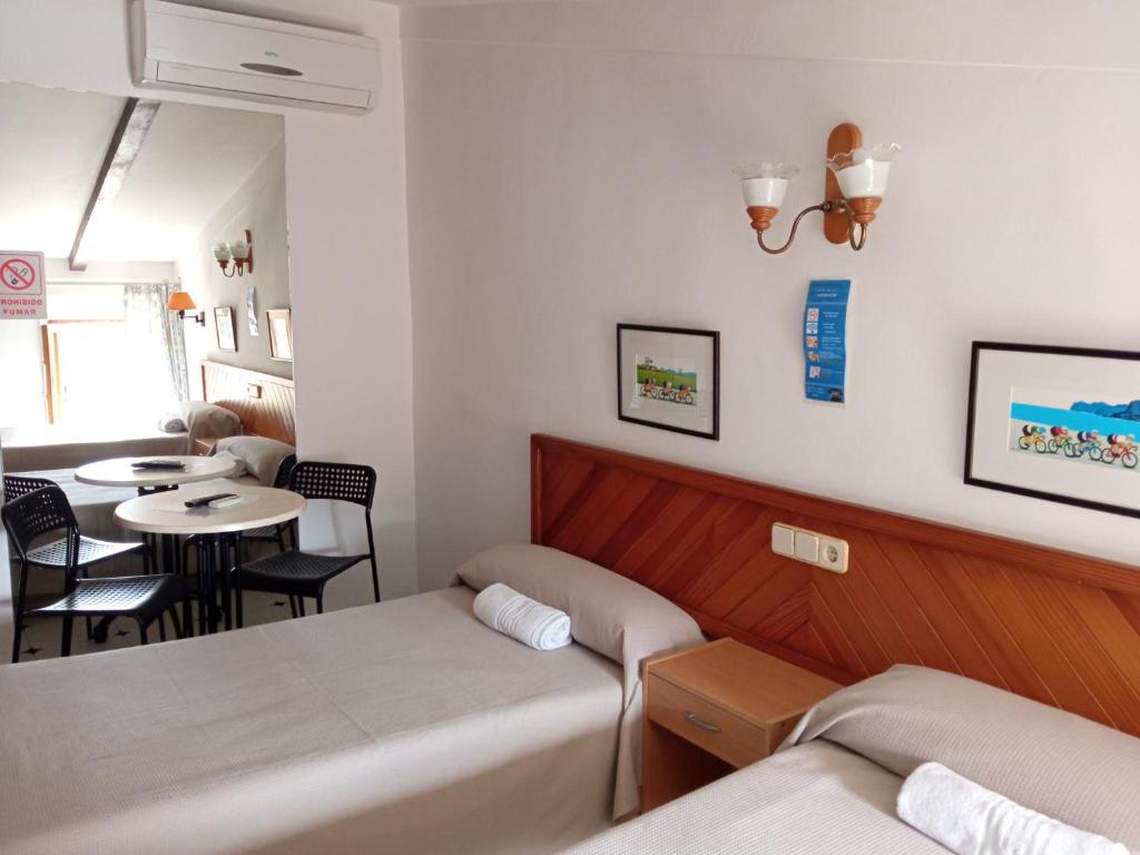 a hotel room with two beds and a desk at Hostal Ca'n Tiu in Alaró