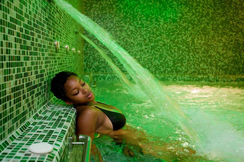 a young child in a swimming pool with a water hose at Danai Hotel & Spa in Olympic Beach