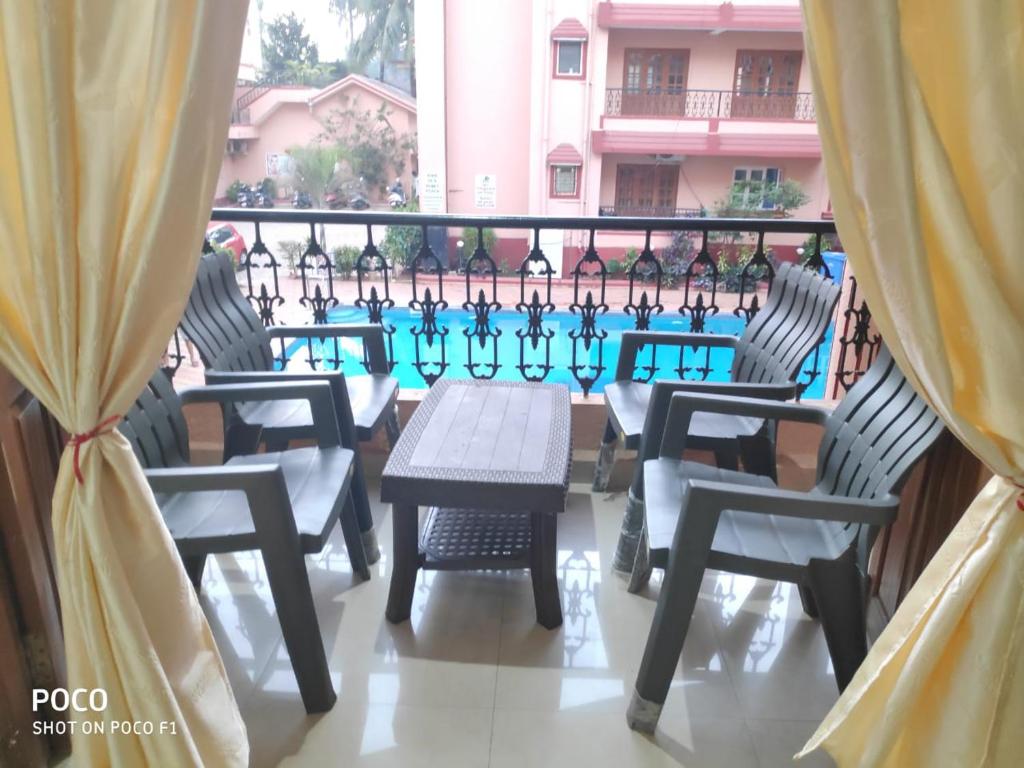 卡蘭古特的住宿－2 bhk Calangute - Baga road Saldanha Kyle Gardens，一个带桌椅的阳台和一个游泳池