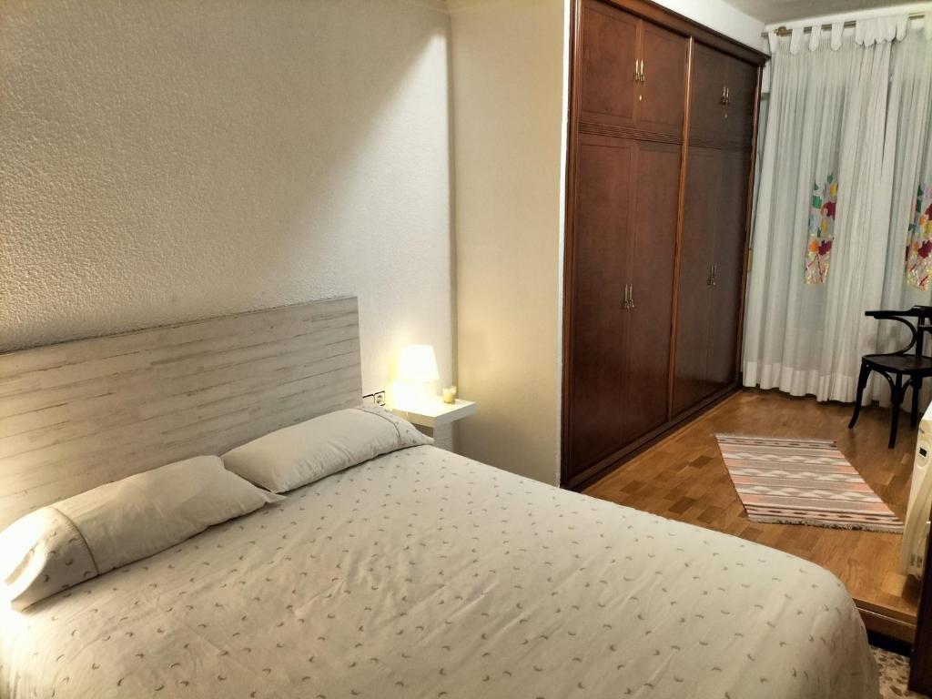 1 dormitorio con 1 cama blanca grande y cabecero de madera en Piso Centro María Aire-Wifi, en Elche