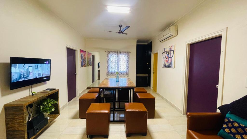 ein Wohnzimmer mit einem Sofa, einem TV und Stühlen in der Unterkunft 2bhk Luxury Penthouse (the north face) in Jaipur