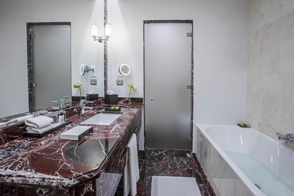 a bathroom with two sinks and a tub and a large mirror at InterContinental Porto - Palacio das Cardosas by IHG in Porto