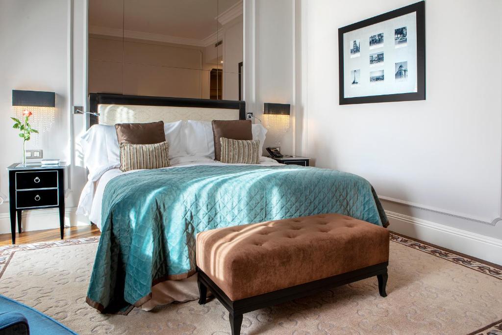 a bedroom with a bed with a blue blanket and a stool at InterContinental Porto - Palacio das Cardosas by IHG in Porto