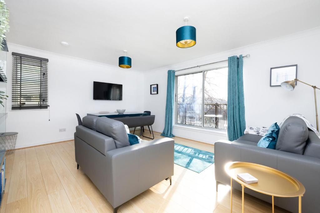 a living room with two couches and a table at JOIVY Bright 3-bed flat overlooking The Clyde in Glasgow