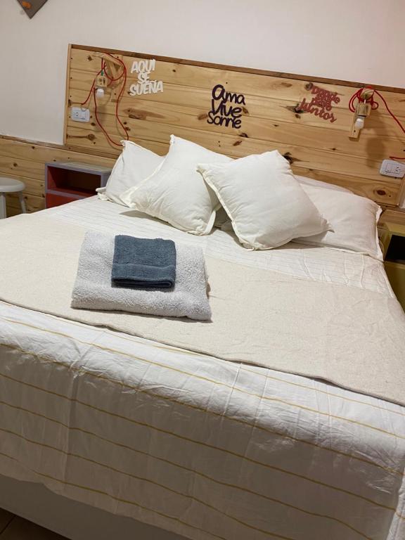 uma cama com almofadas brancas e uma toalha azul em Hostal Asqui Pacha em Tilcara