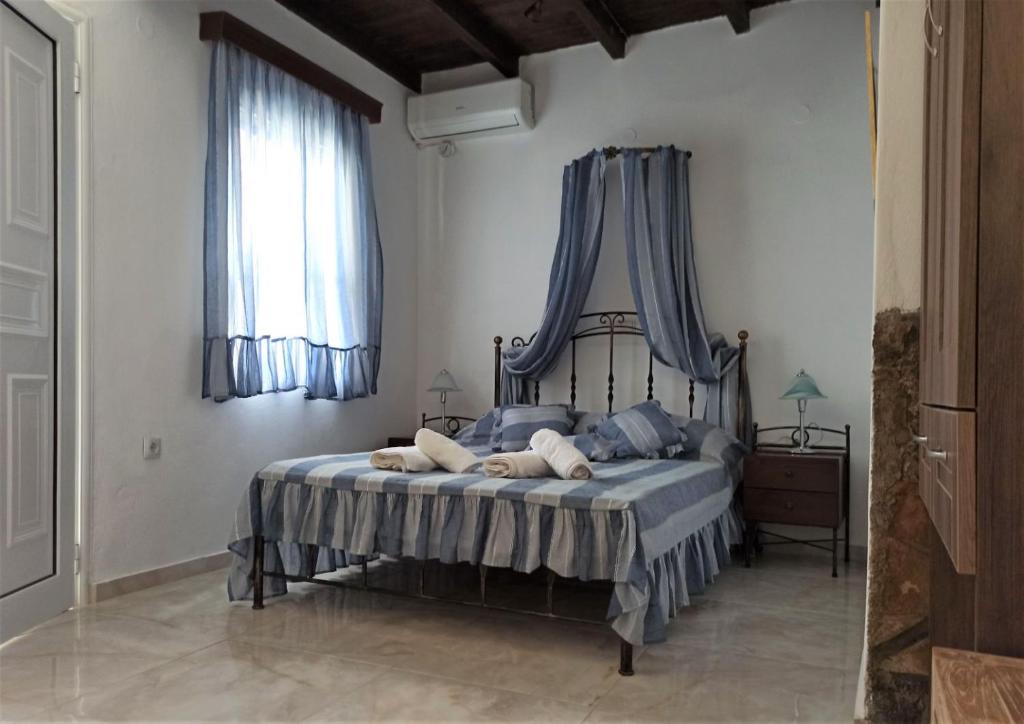 a bedroom with a bed with blue drapes at Alexandros by the Beach - Serifos in Livadakia
