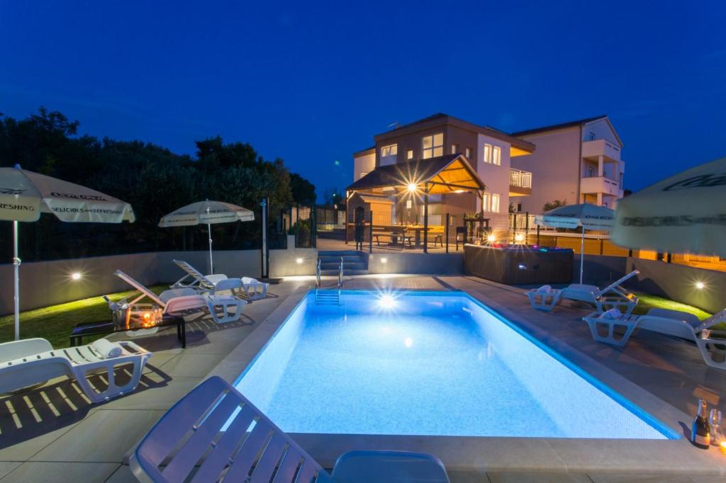 einen Pool mit Stühlen und ein Haus in der Unterkunft VILLA HONEY, Seget - Trogir in Seget Vranjica