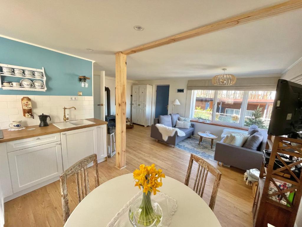 eine Küche und ein Wohnzimmer mit einem Tisch mit Blumen darauf in der Unterkunft Charzykówka Domek na Kaszubach in Charzykowy